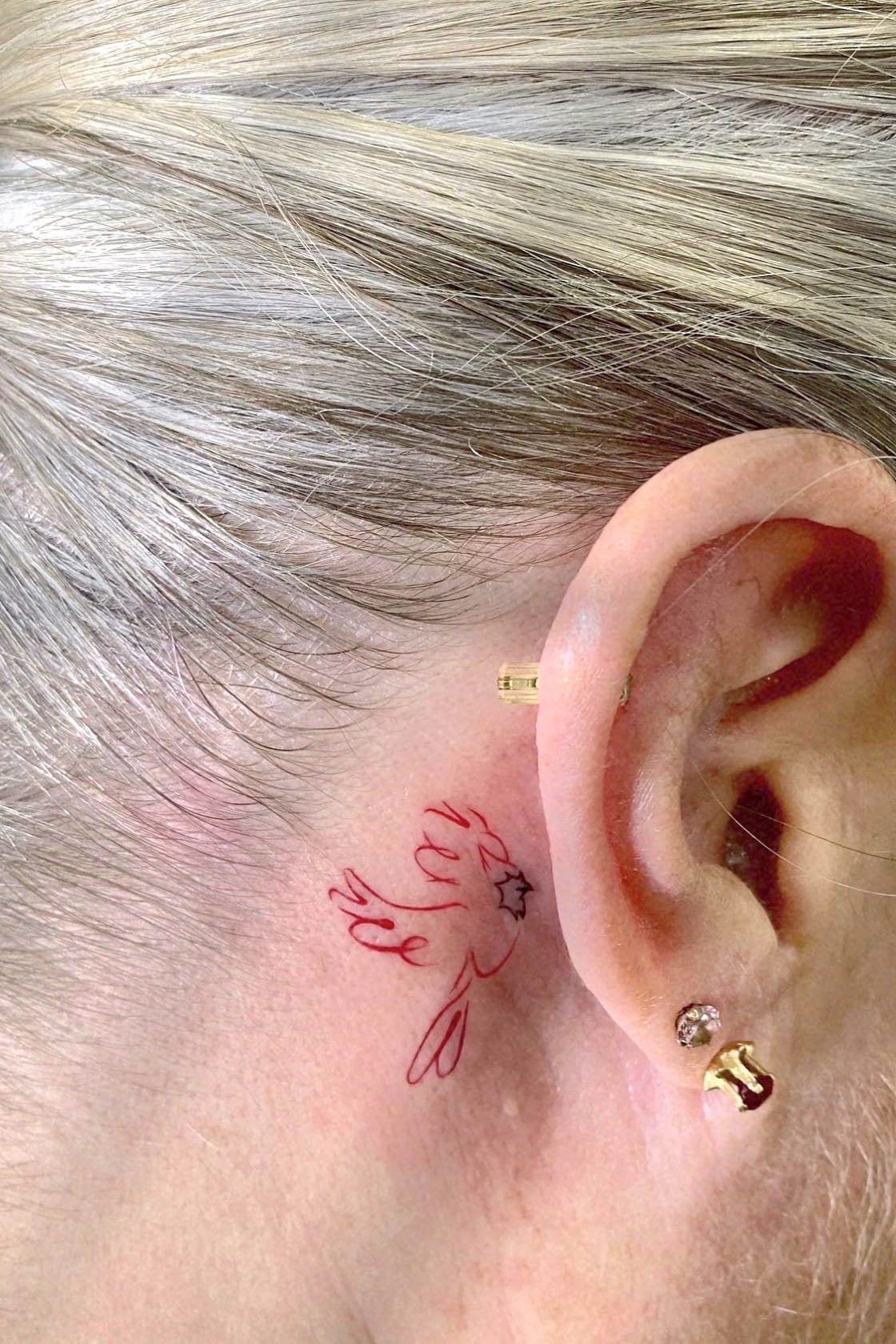 Small cardinal tattoo behind ear